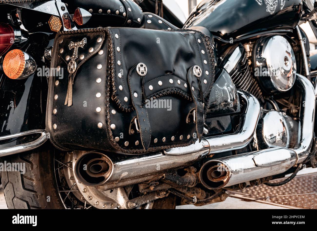 Primo piano di una moto nera d'epoca con tubi di scarico cromati e borse in pelle Foto Stock