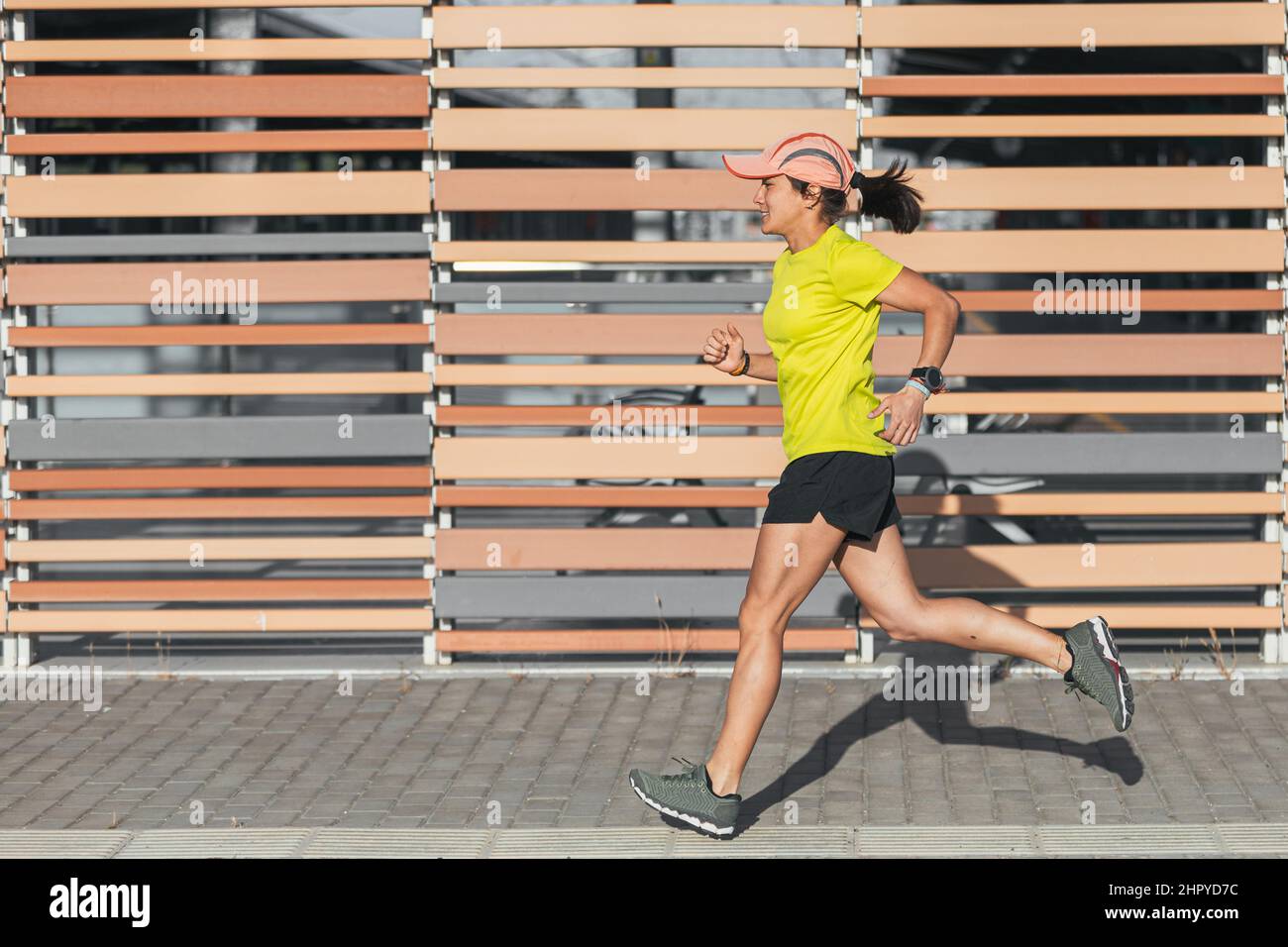 Latina donna che corre all'aperto in profilo con uno stile di vita sano. Colore giallo Foto Stock