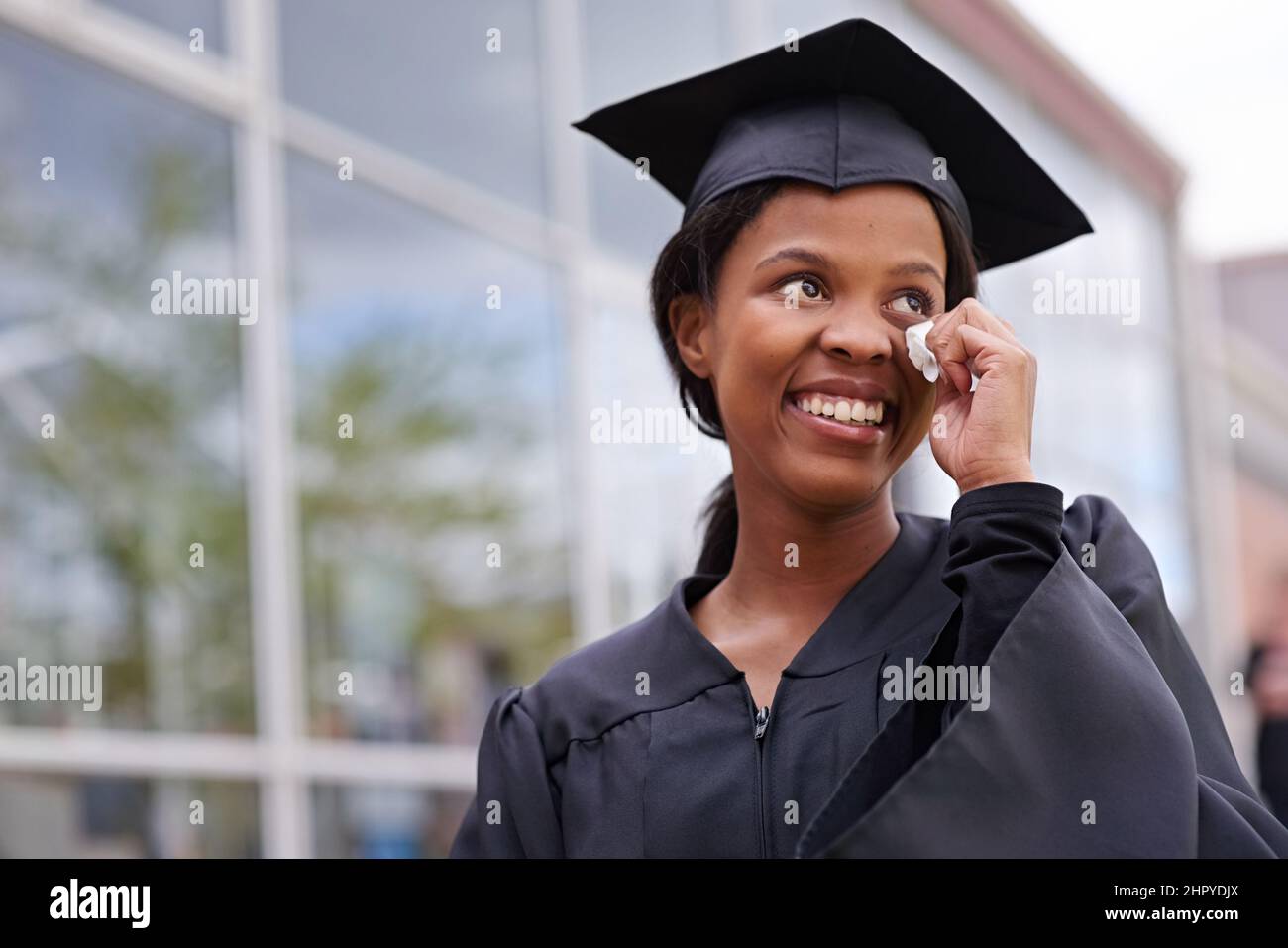 Tanto per essere grati. Ritratto di uno studente africano bello spazzare via le lacrime di gioia nel suo giorno di laurea. Foto Stock