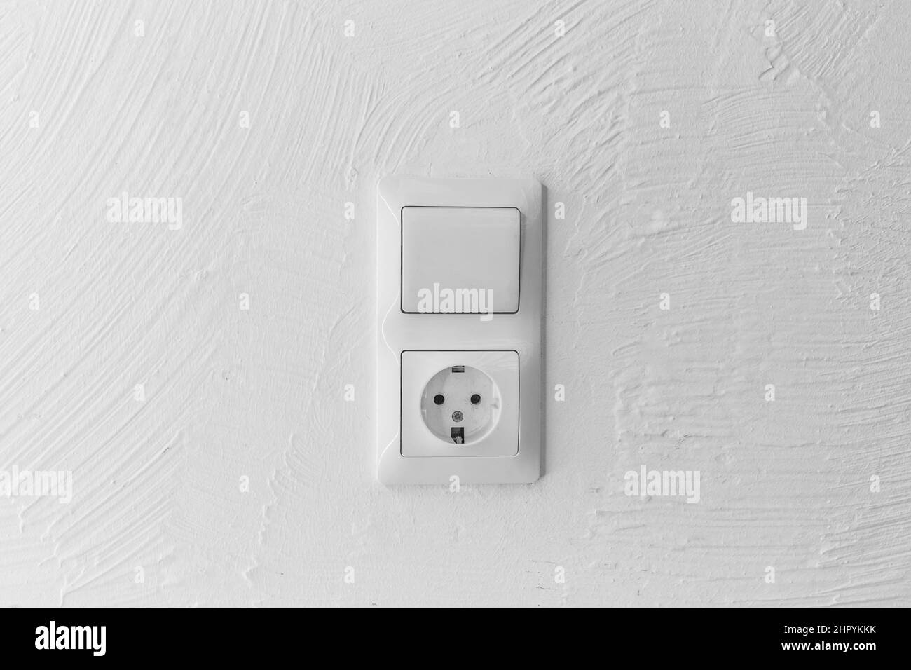 Presa e luce spenta pulsante di accensione sullo sfondo della parete bianca dell'interruttore della casa, da vicino. Foto Stock