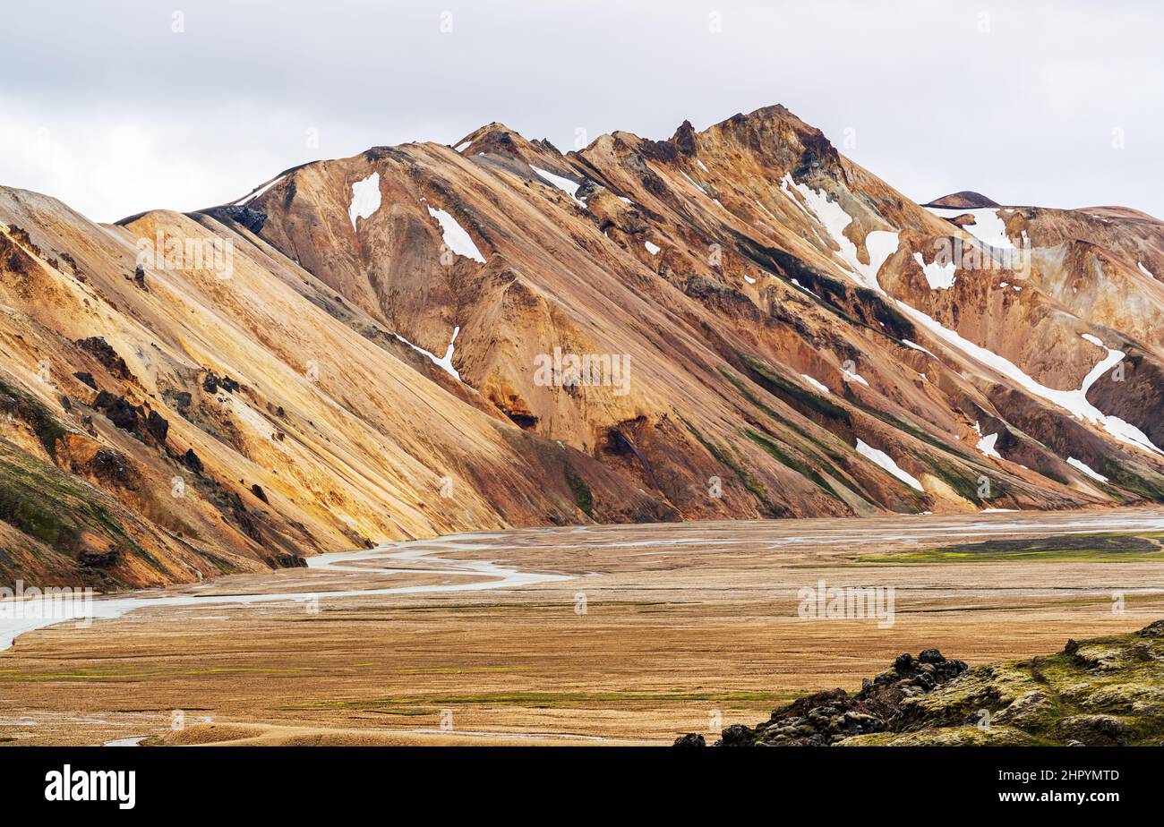 Paesaggio impressionante a Landmannalaugar Valley in Highlands. Montagna di neve colorata sopra l'aereo e il fiume. Foto Stock