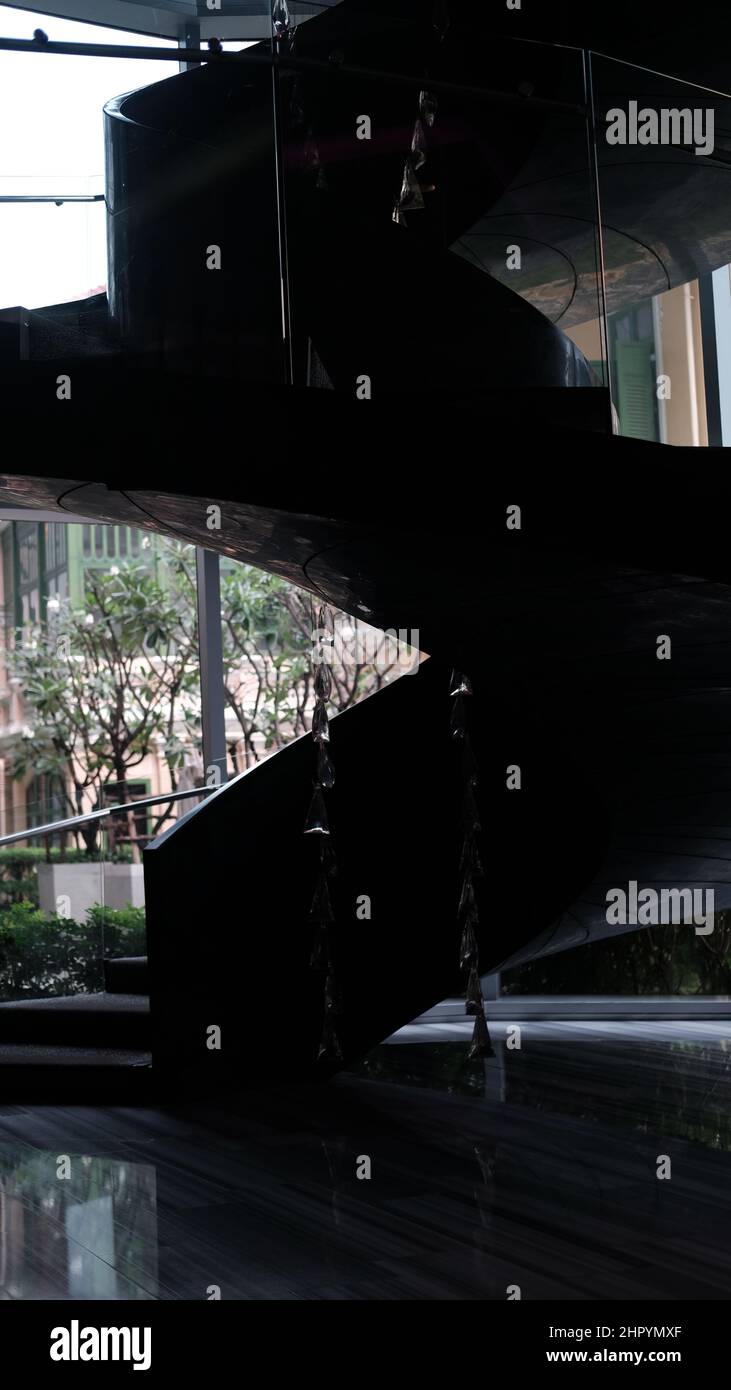 Silhouette scura di novità a piedi su scala a chiocciola curva in uno spazio tridimensionale Foto Stock