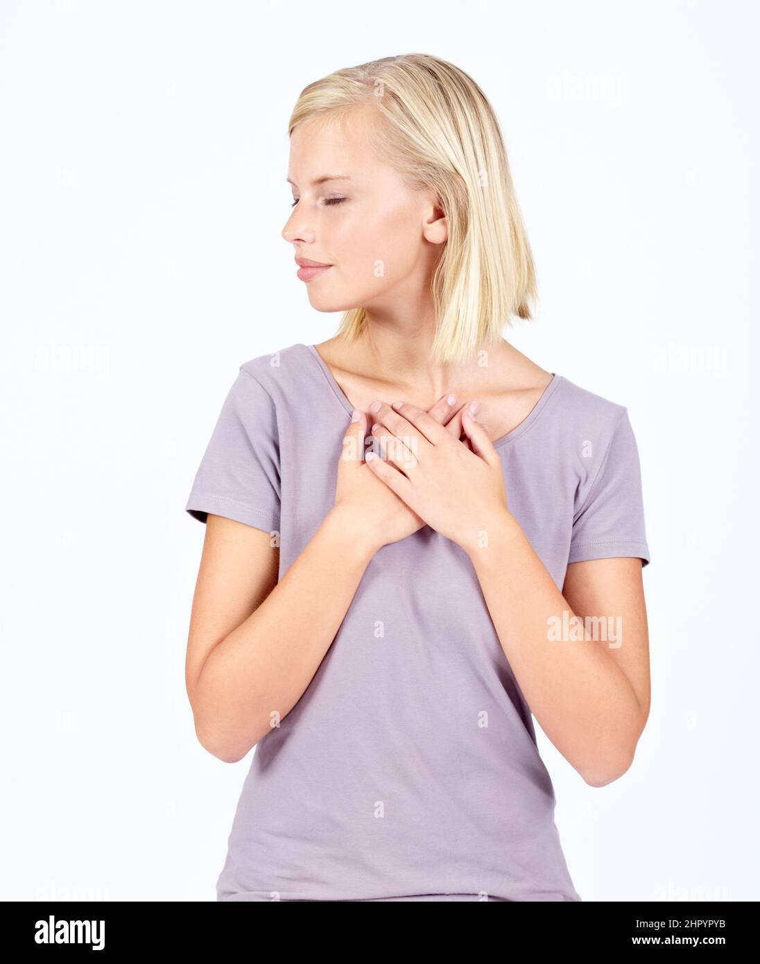 Tenere l'amore. Bella giovane donna isolato su bianco tenendo le mani al suo petto. Foto Stock