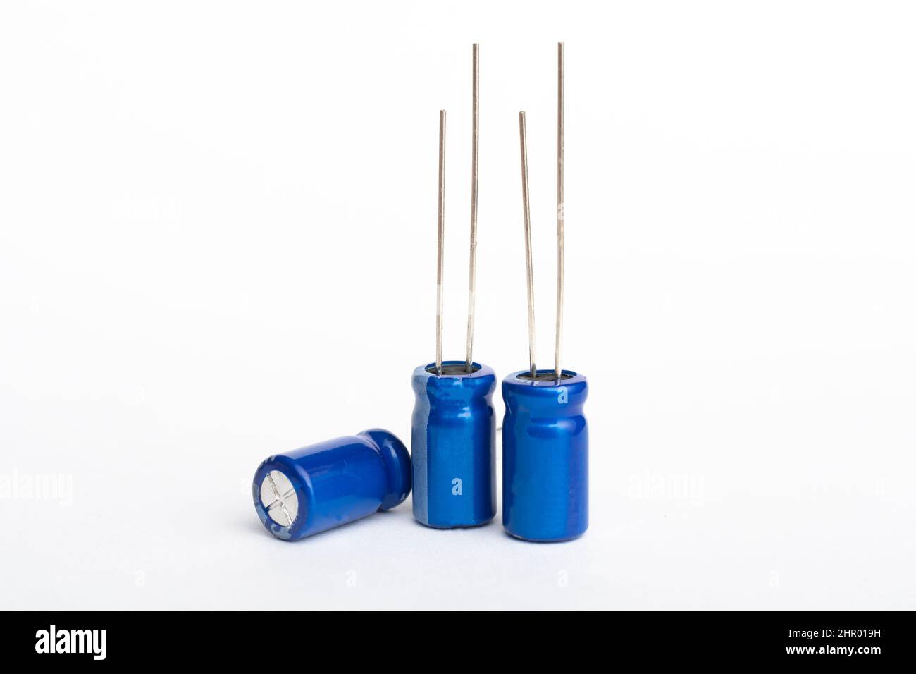 Tre condensatori elettrolitici blu isolati su sfondo bianco Foto Stock