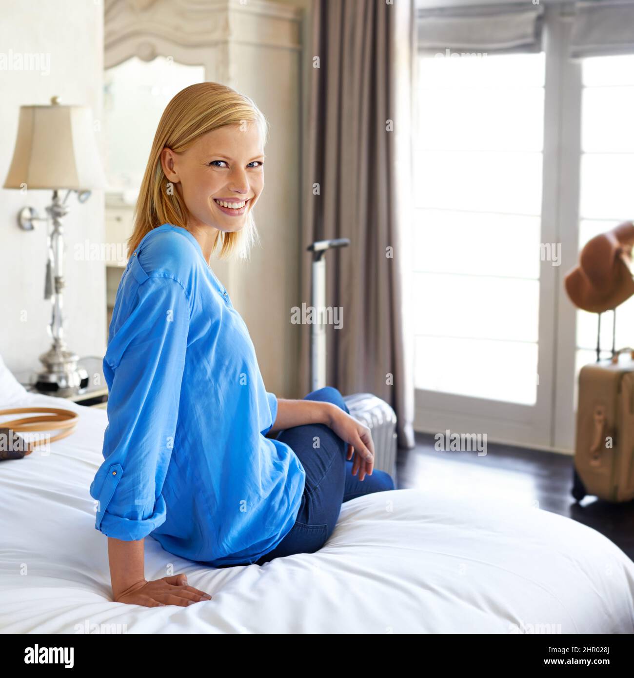 Sembra felice con la sua camera d'albergo. Scatto corto di una giovane donna attraente che si rilassa sul letto della sua camera d'albergo. Foto Stock