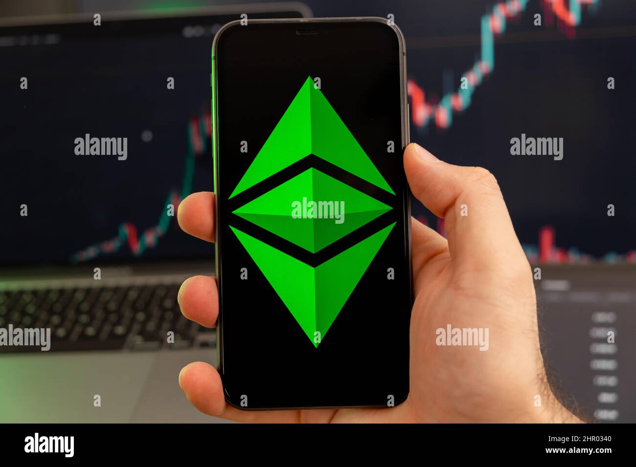 Ethereum Classic ETC app di criptovaluta analisi del mercato azionario sullo schermo del telefono cellulare in mani di uomo e crescente grafici di scambio dati sullo sfondo, febbraio 2022, San Francisco, USA. Foto Stock