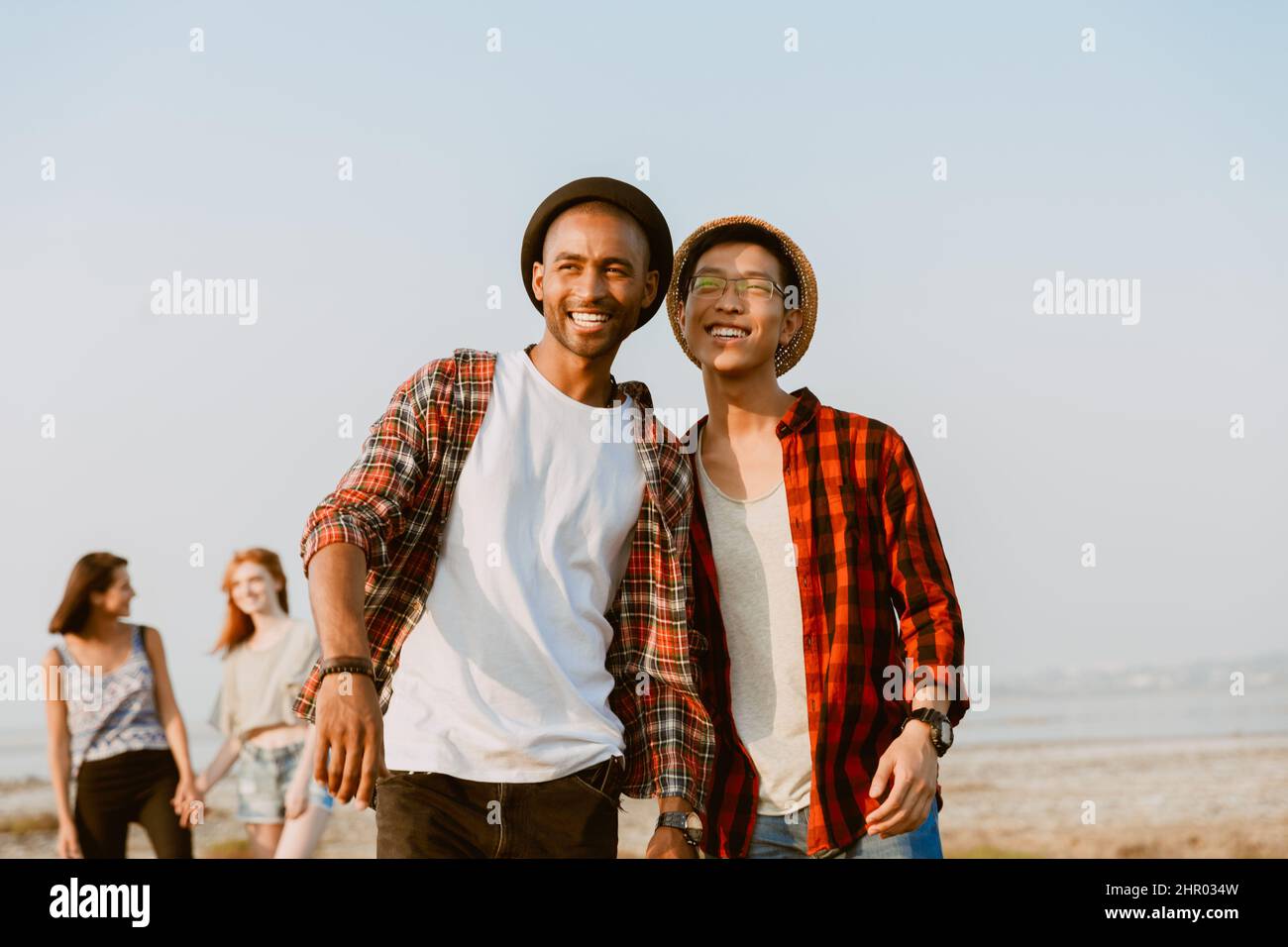 Giovani amici multirazziali ridono e guardano da parte mentre camminano all'aperto Foto Stock