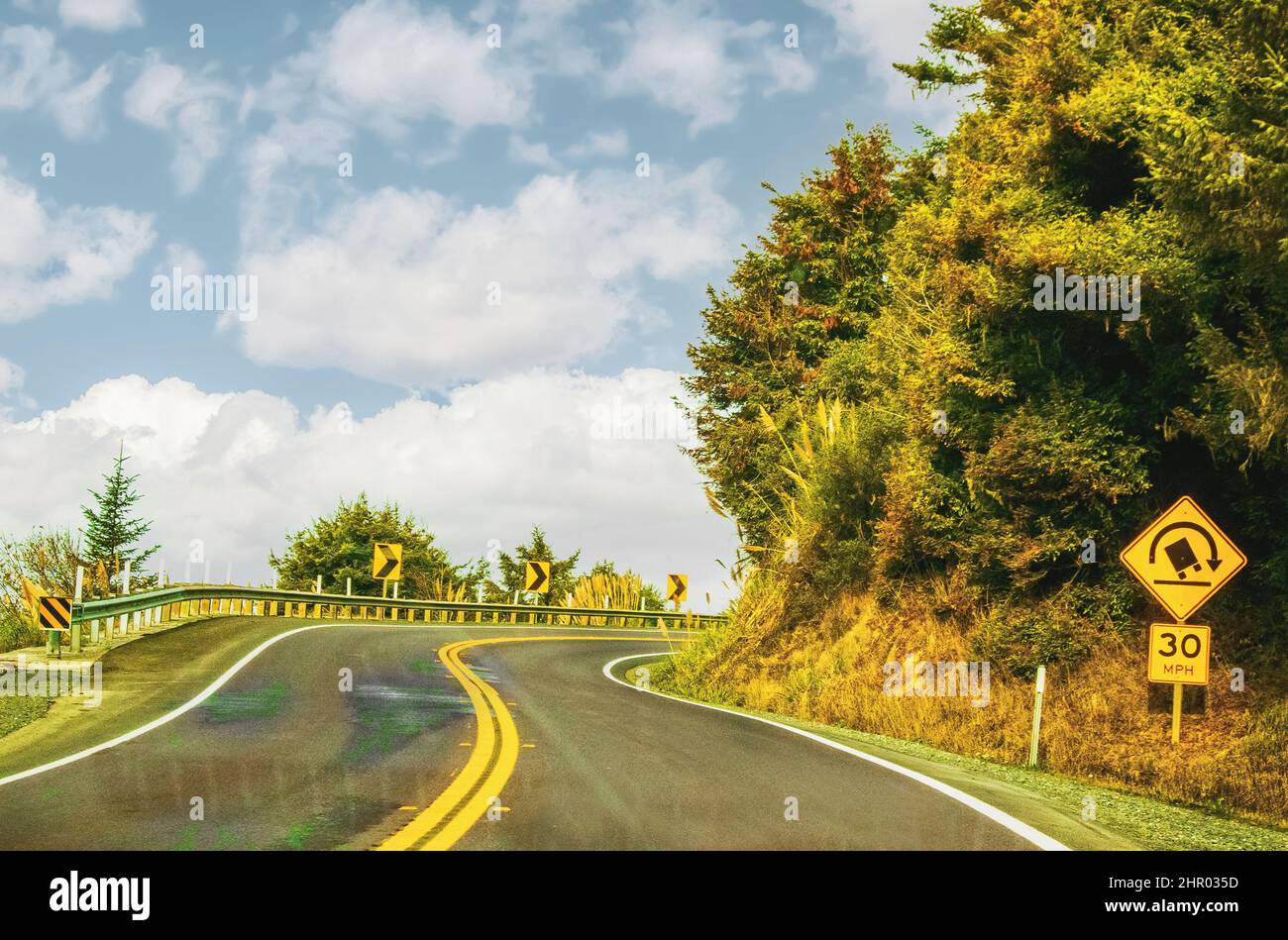 Strada di montagna curva con guardrail e segno di camion ribaltamento Foto Stock