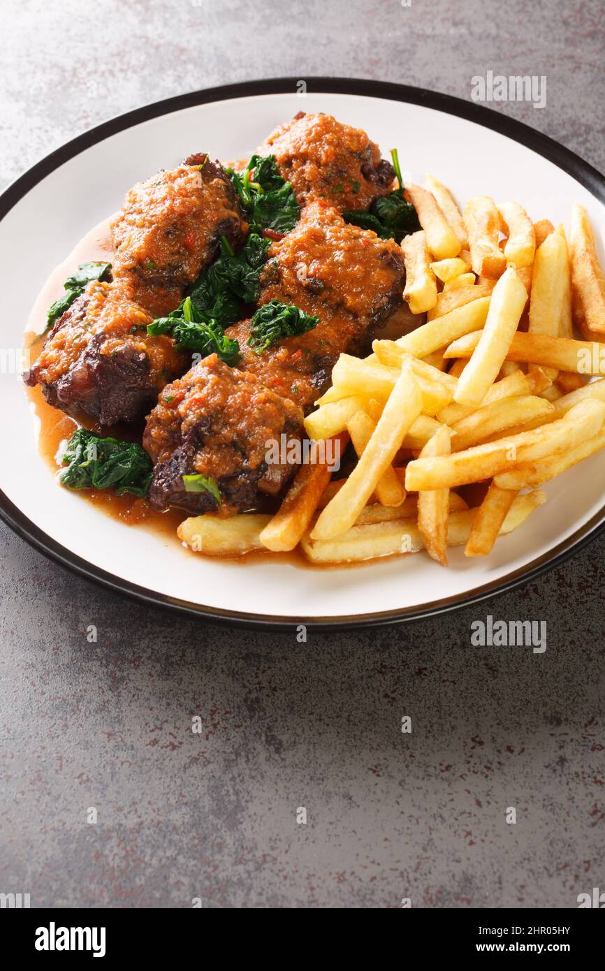 Rabo De Toro delizioso piatto in Spagna è stufato di coda di bue servito con il primo piano di frittura francese nel piatto sul tavolo. Verticale Foto Stock