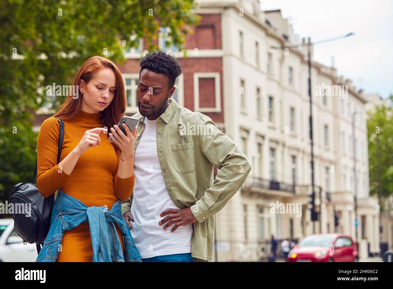 Giovane coppia che viaggia insieme in città seguendo le indicazioni sull'app Map sul telefono cellulare Foto Stock