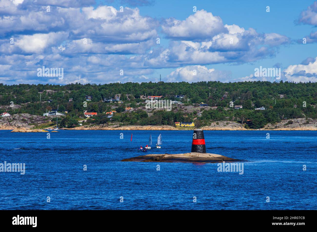 Strömstad, Bohuslän, Västra Götalands Län, Svezia - 11 agosto 2016: Piccole barche a vela al largo della costa vicino a uno skerry con un marchio di mare. Foto Stock