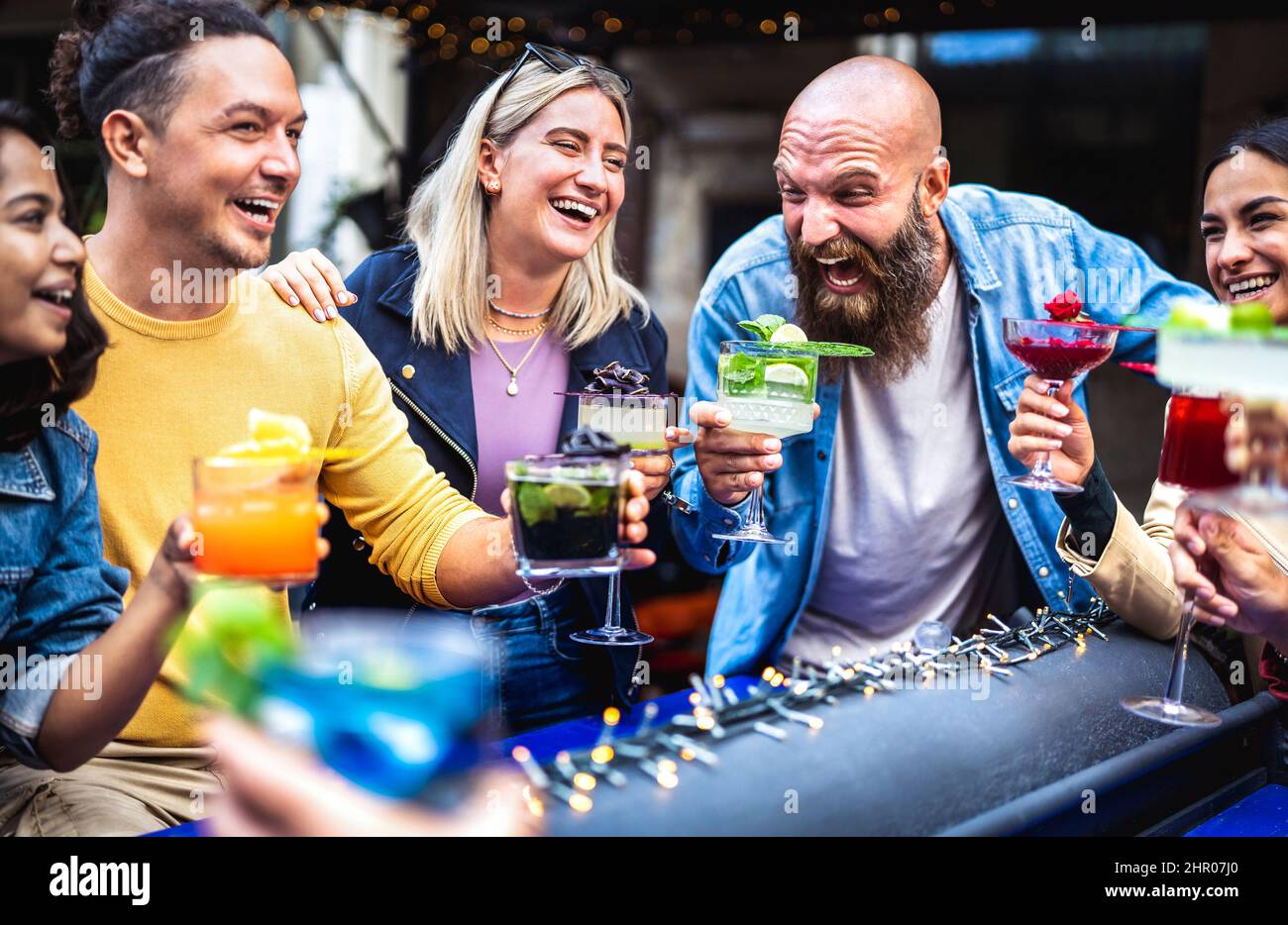 Giovani alla moda che tostano bevande fresche multicolore al bar alla moda - amici di Gen z divertirsi insieme a bere cocktail durante l'happy hour - cibo e. Foto Stock