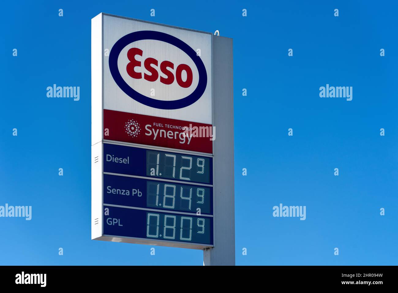 Fossano, Italia - 22 febbraio 2022: Segno del logo esso con carburante visualizzazione del prezzo dell'euro sul cielo blu, esso è un marchio del gigante mondiale dell'industria petrolifera ExxonMob Foto Stock