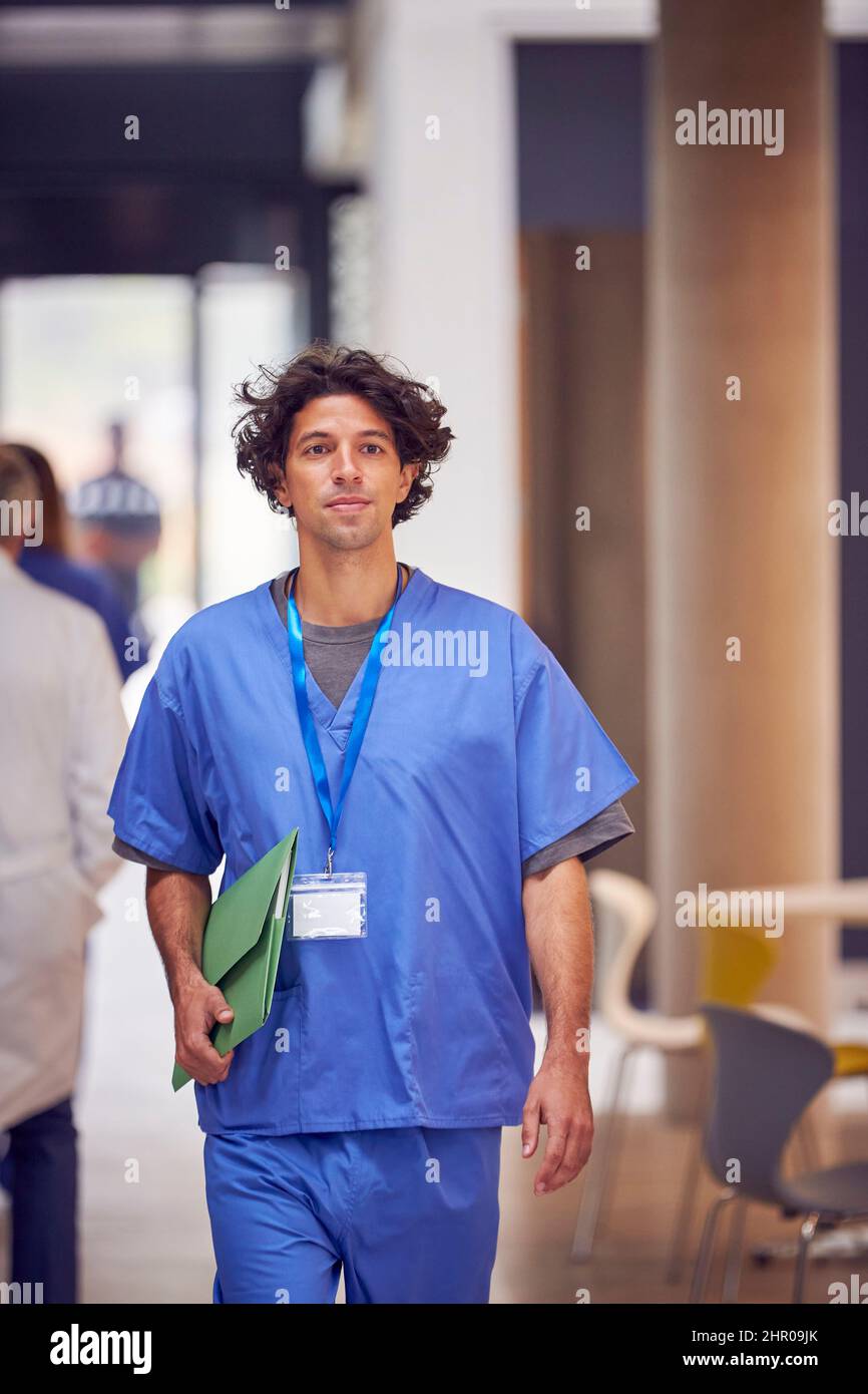 Maschio medico indossare scrub portare paziente Note camminare in ospedale occupato Foto Stock