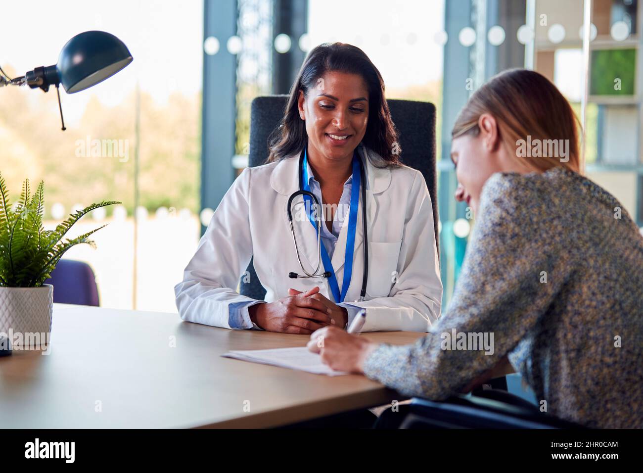 Donna medico ottenere donna paziente firmare modulo di consenso in Ufficio ospedaliero Foto Stock
