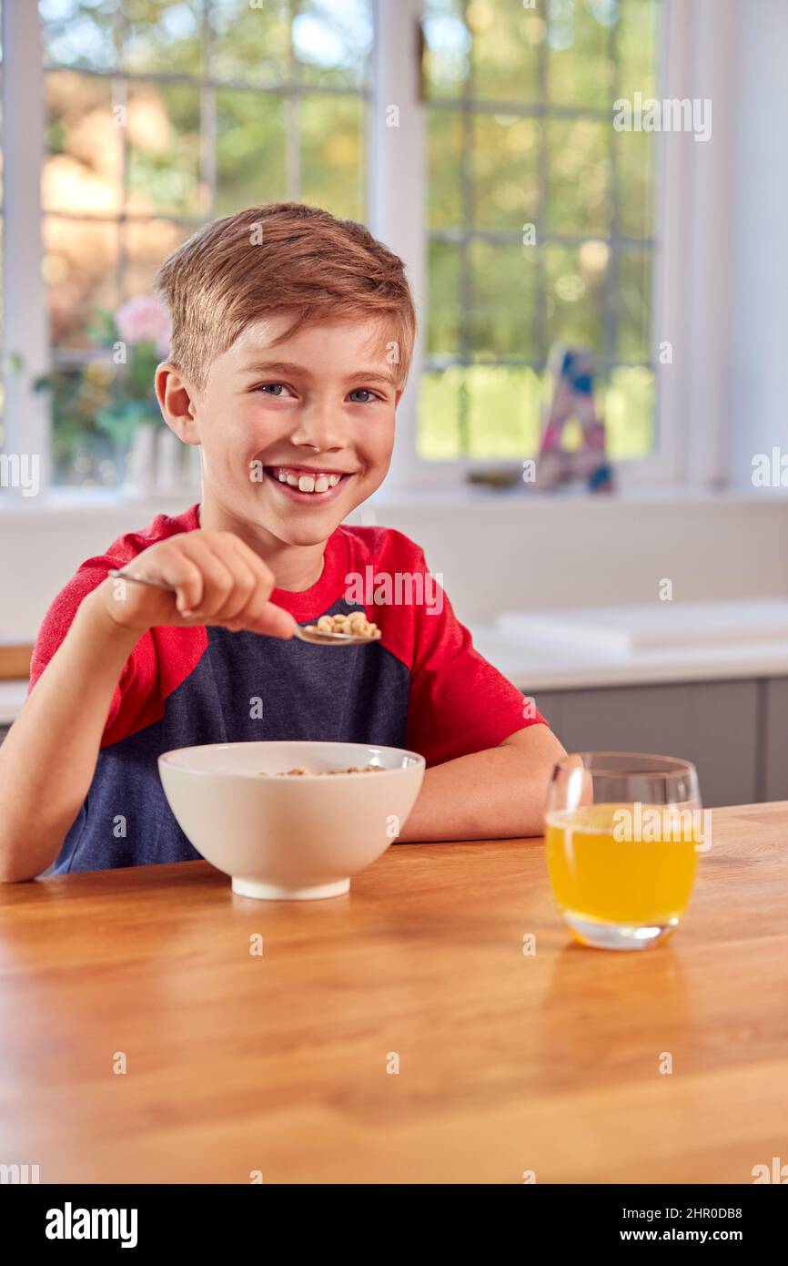 Ritratto di Boy a casa mangiare ciotola di cereali colazione al banco cucina Foto Stock