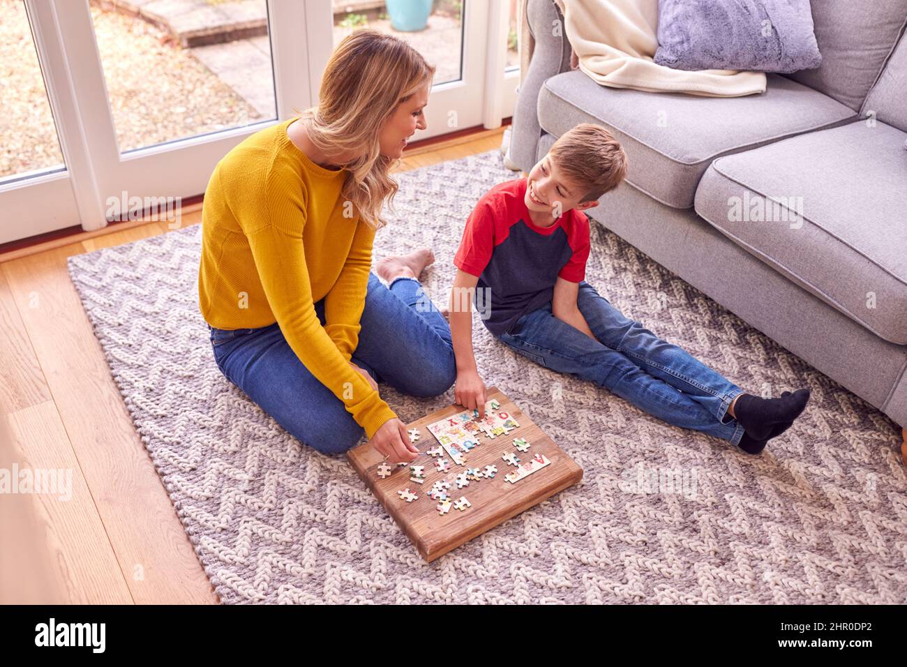 Madre e figlio a casa fare Jigsaw Puzzle al piano della sala insieme Foto Stock