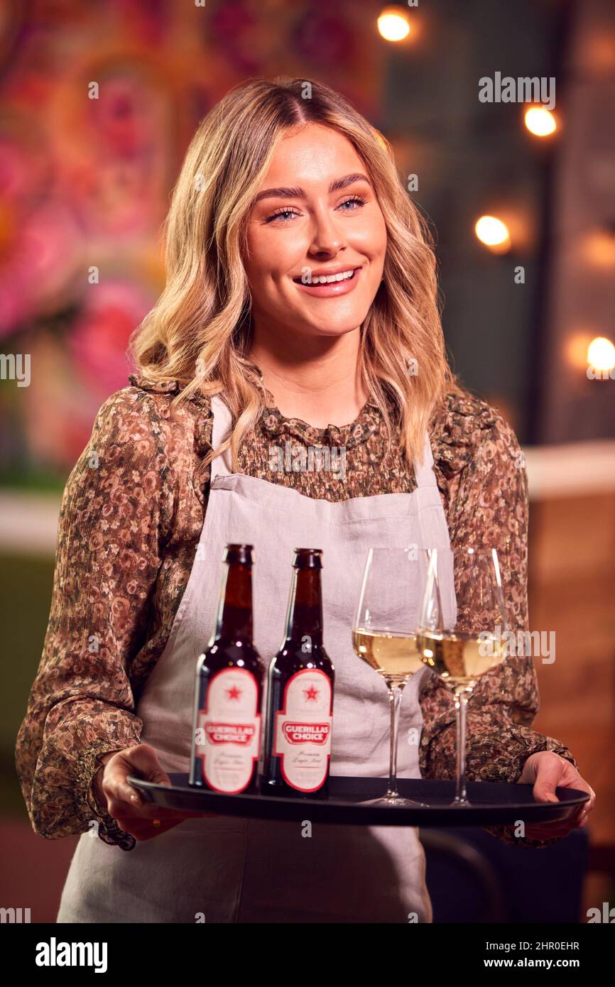 Ritratto di Smiling Female Server Holding vassoio di bevande al Cool Bar o Club Foto Stock