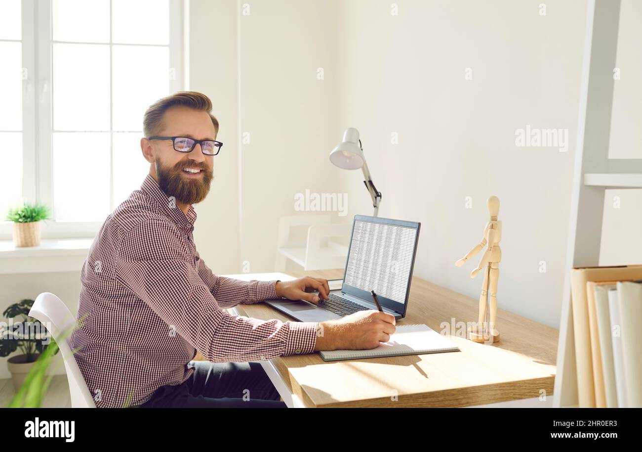 Ritratto di uomo d'affari che lavora su un computer portatile con documenti elettronici in ufficio. Foto Stock