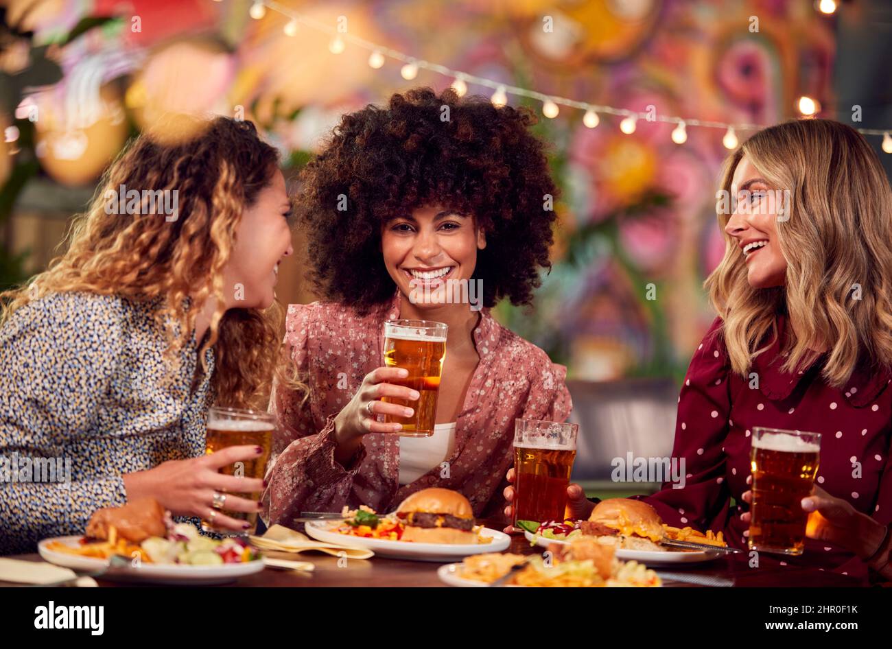 Gruppo multiculturale di amici di sesso femminile che si godono la Notte fuori mangiare pasto e bere in Ristorante Foto Stock