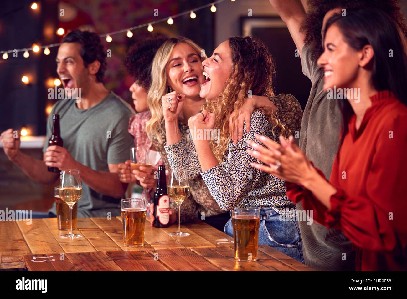 Gruppo di amici che festeggiano il gioco di sport o la partita che beve nel bar insieme Foto Stock
