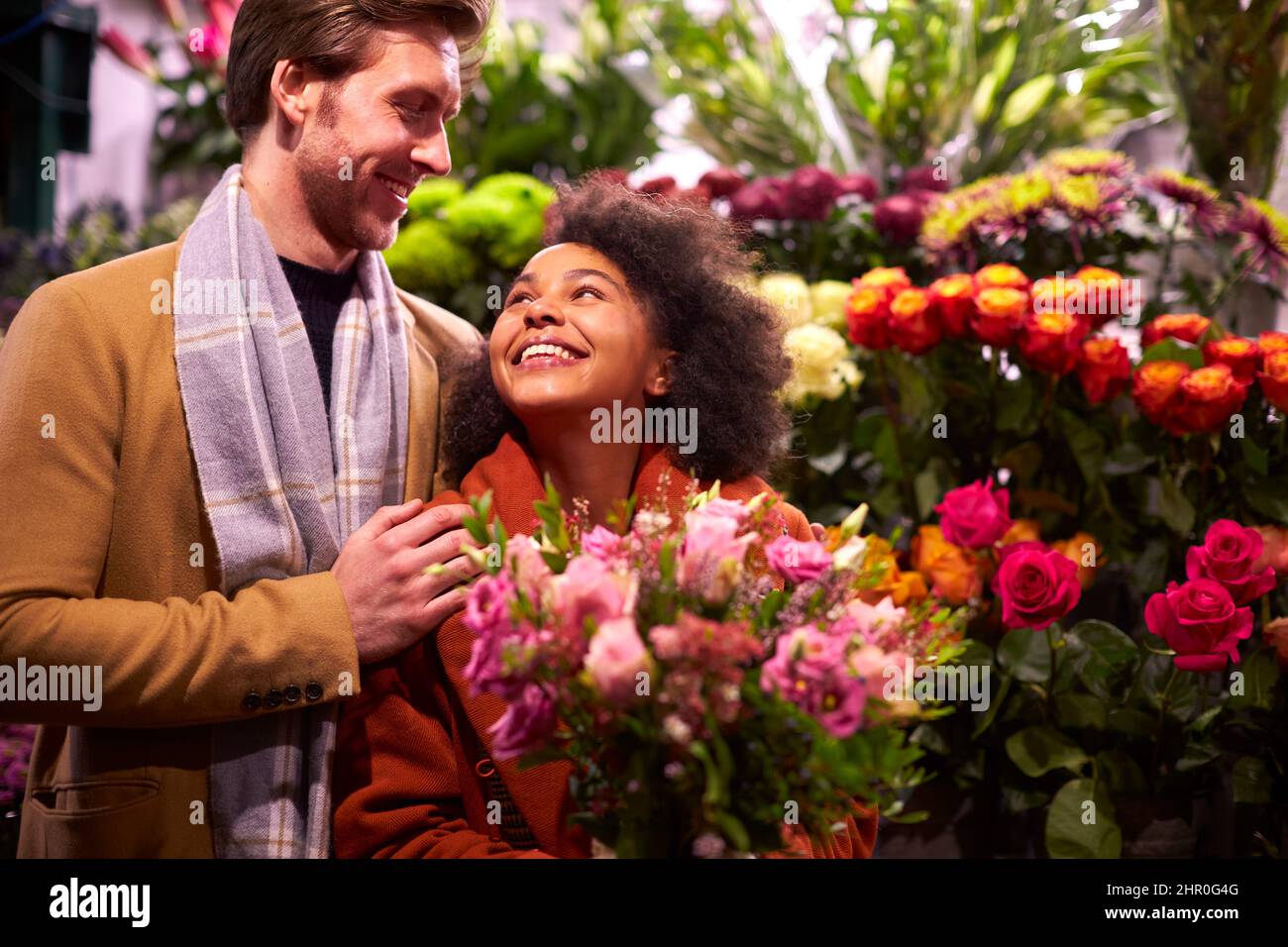 Coppia scegliendo Fiori da Florist Stall al mercato di Natale all'aperto Foto Stock