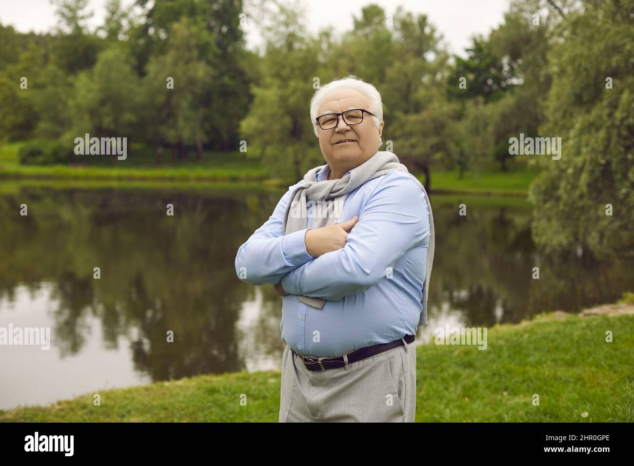 Ritratto di un uomo anziano felice in pensione godendo di pensione a piedi in una giornata estiva nel parco. Foto Stock