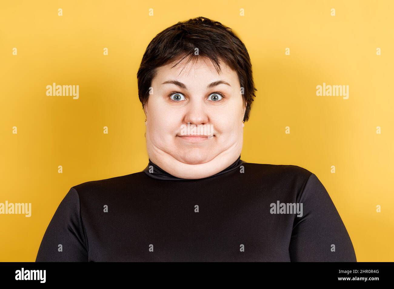 donna grassa con doppio mento e aspetto pazzo su sfondo giallo Foto Stock