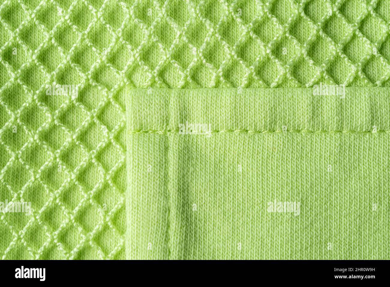 Tasca patch su maglia verde cotone macro. Tessuto in maglia verde chiaro con mesh per un abbigliamento sportivo moderno. Abbigliamento casual. Foto Stock