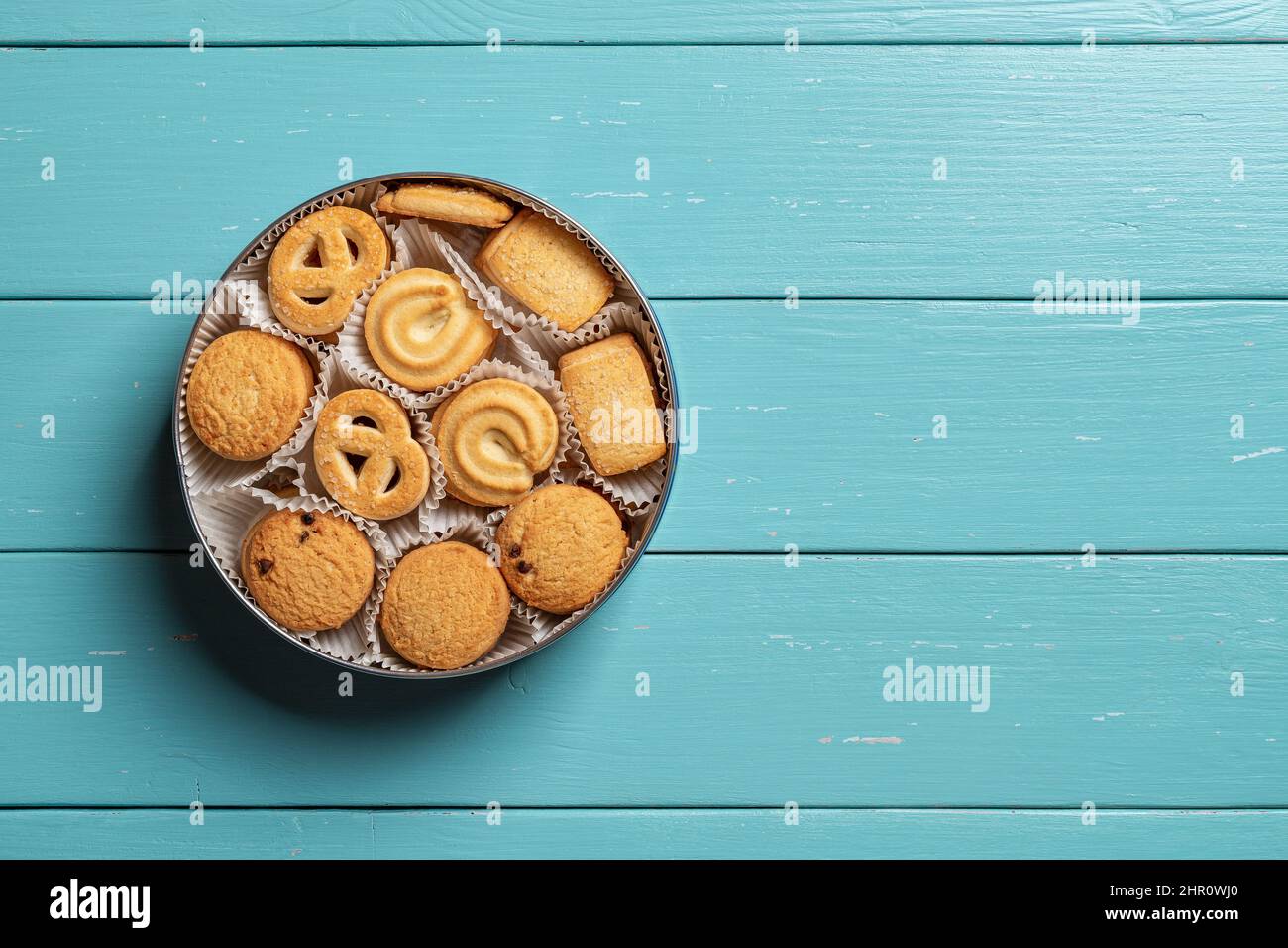 Dolci biscotti danesi al burro in una teglia aperta su un tavolo di legno turchese. Biscotti croccanti assortiti a colazione. Pasticceria al forno. Cibo dolce Foto Stock