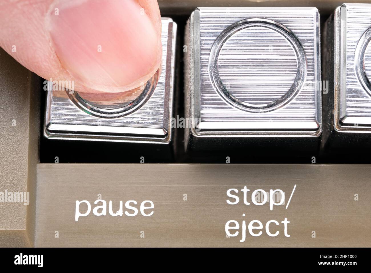 Il dito ha premuto un pulsante di pausa di una macro di registratore di nastri vintage Foto Stock