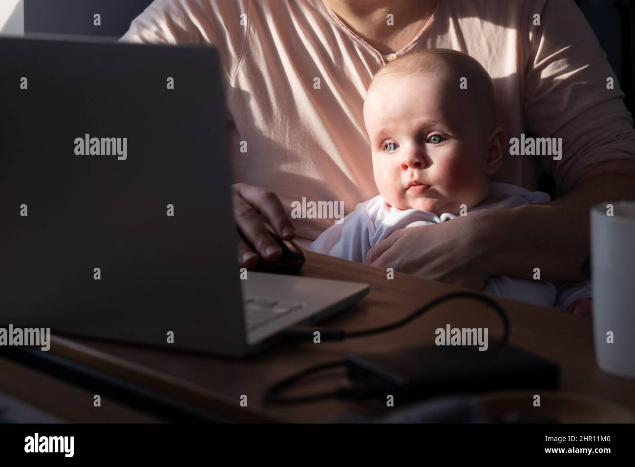 Babysitting caucasico con sua madre usando il portatile Foto Stock