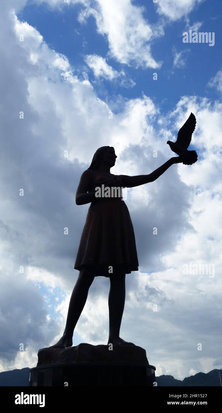 La statua della ragazza sta tenendo e rilasciando l'uccello alla libertà Foto Stock