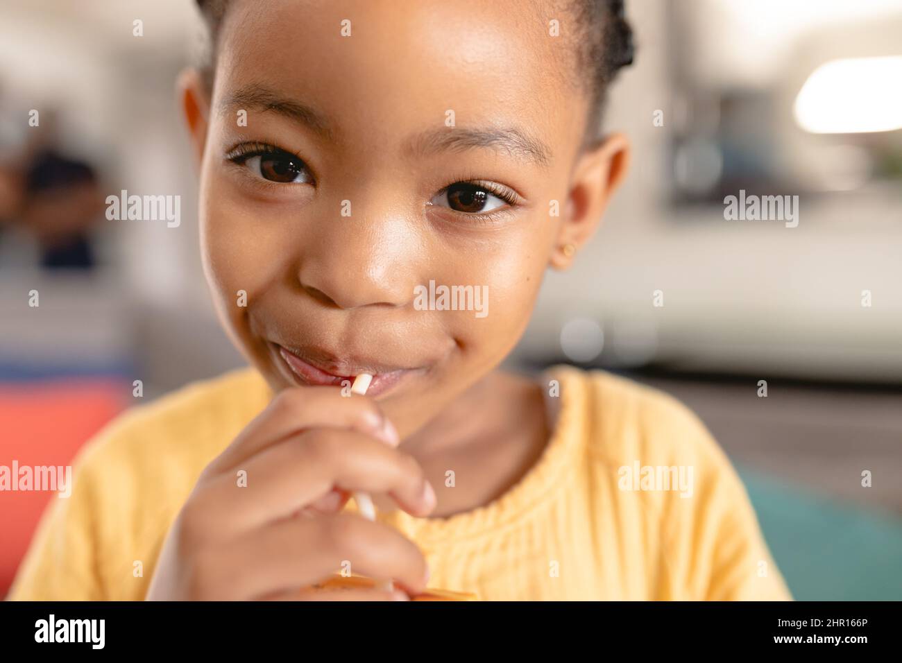 Primo piano ritratto di carina ragazza afroamericana che mangia lollipop a casa Foto Stock