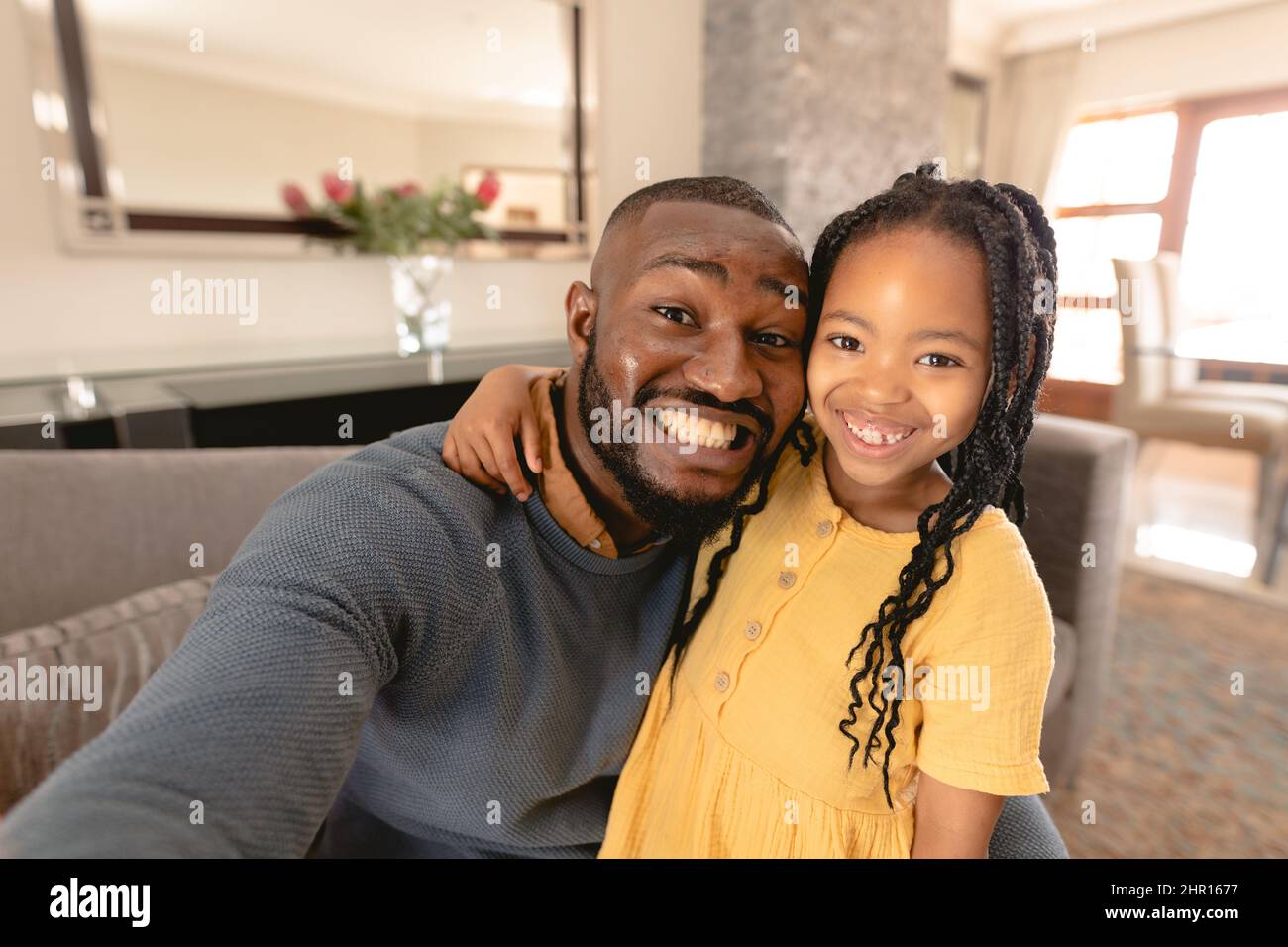 Ritratto di sorridente padre e figlia afroamericana che prende insieme selfie seduto a casa Foto Stock