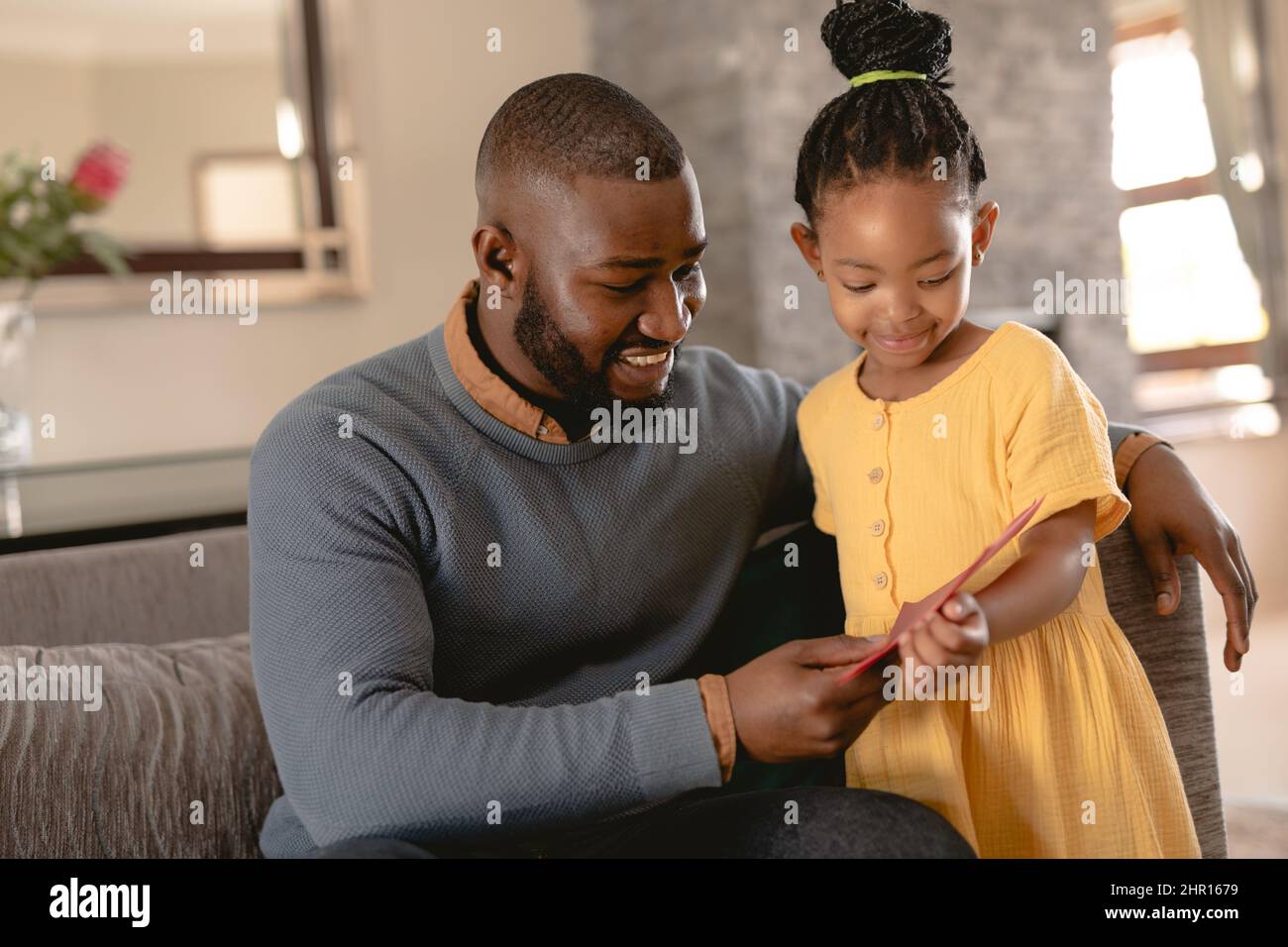 Felice afro-americano padre e figlia lettura biglietto di auguri in soggiorno a casa Foto Stock