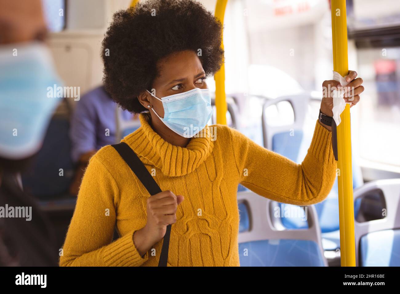 African american metà adulta businesswoman indossare maschera di tenuta maniglia con tovagliolo in autobus Foto Stock