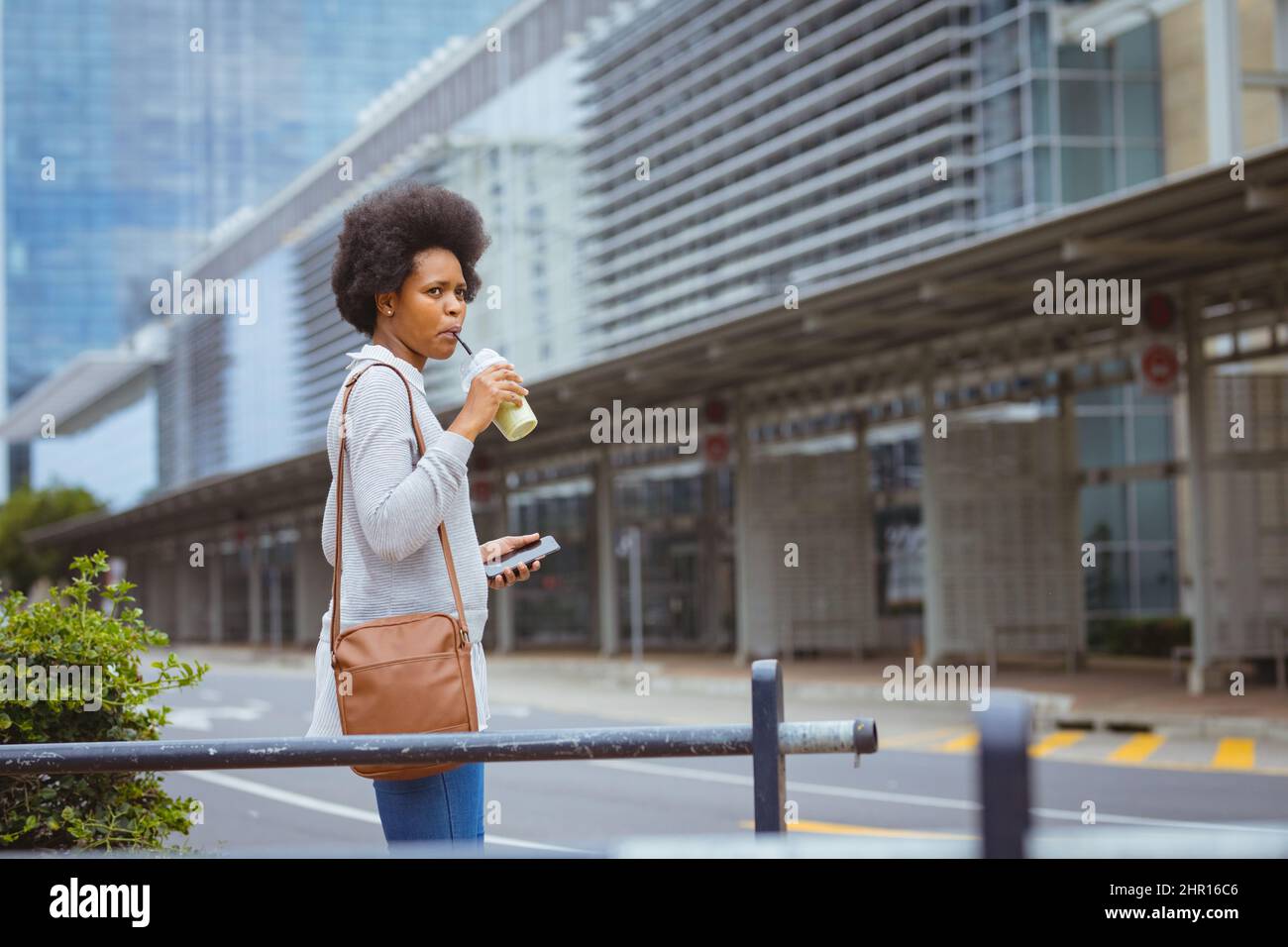 Donna d'affari afroamericana di metà adulto che ha bevuto guardandosi via mentre si levano in piedi in città Foto Stock