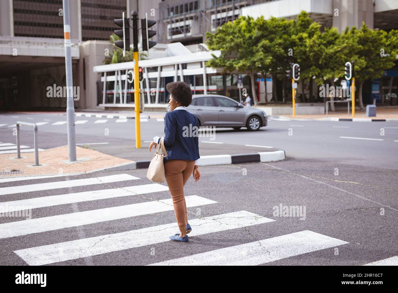 Tutta la lunghezza della donna d'affari afroamericana di medio adulto che cammina sul crosswalk mentre attraversa la strada Foto Stock