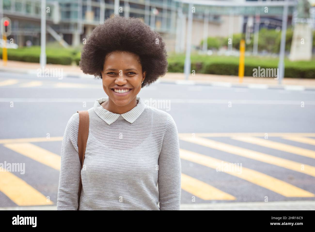 Ritratto di sorridente uomo d'affari afroamericano adulto con capelli afro in piedi su strada in città Foto Stock