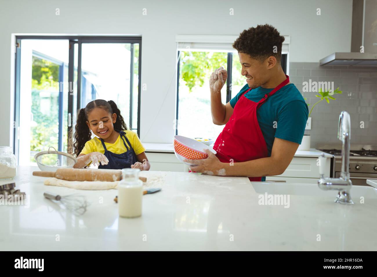 Sorridendo l'uomo biracale godendo di cucinare il pasto con la figlia in cucina a casa Foto Stock