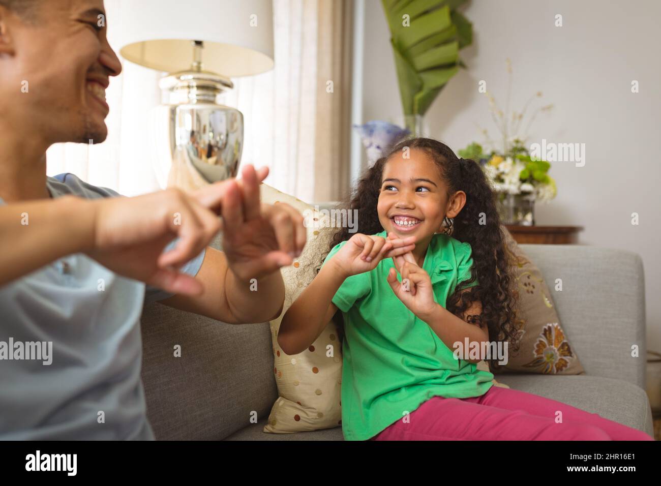 Felice padre e figlia multirazziale che parlano attraverso il linguaggio dei segni a mano a casa Foto Stock