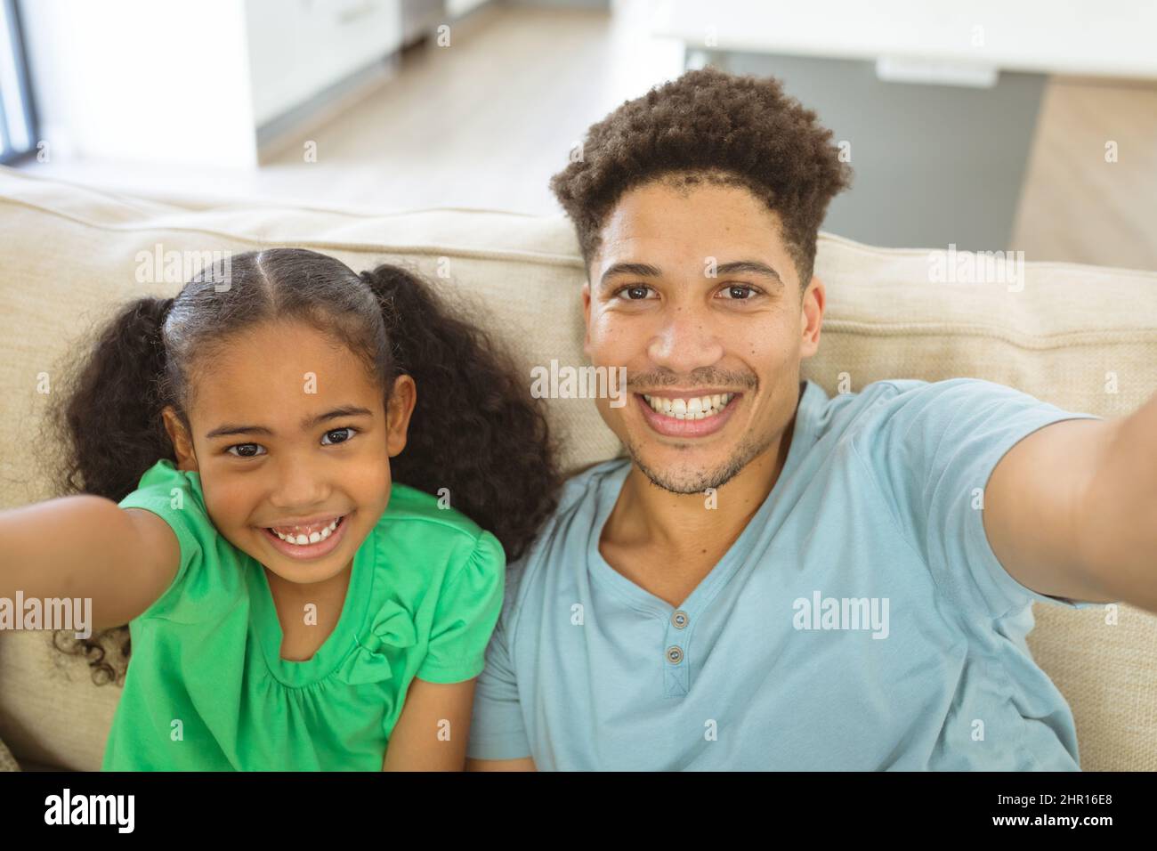 Ritratto di sorridente padre e figlia multirazziale prendendo selfie in soggiorno a casa Foto Stock
