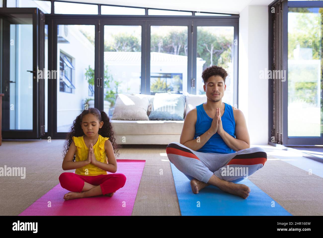 Tutta la lunghezza del padre e della figlia del biracial meditating insieme mentre praticano lo yoga nel paese Foto Stock