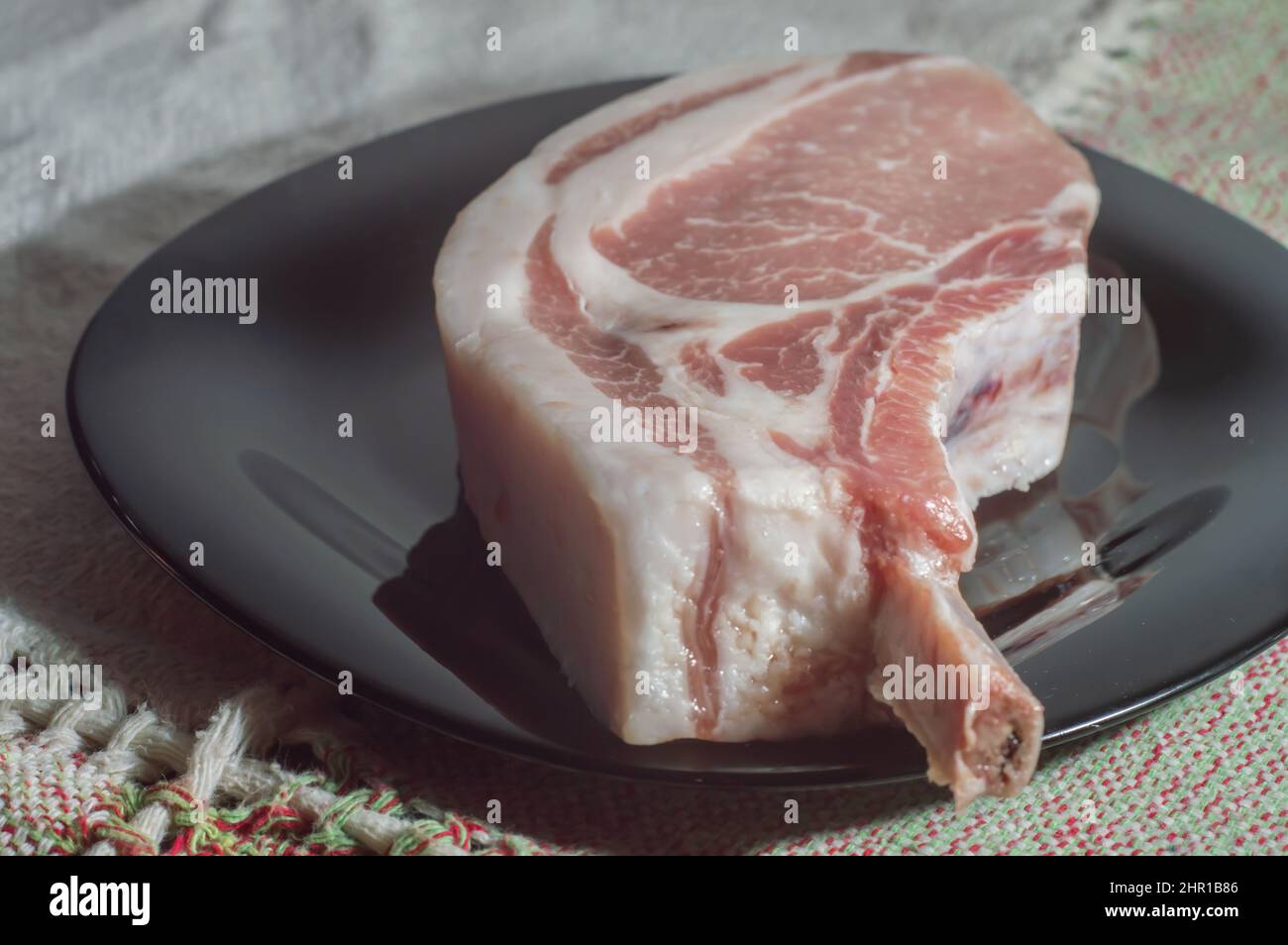 Bistecche di maiale crude di Tomahawk su piastra nera, vista dall'alto. Tre bistecche di maiale crude, pronte per la griglia con vista dall'alto. Foto Stock