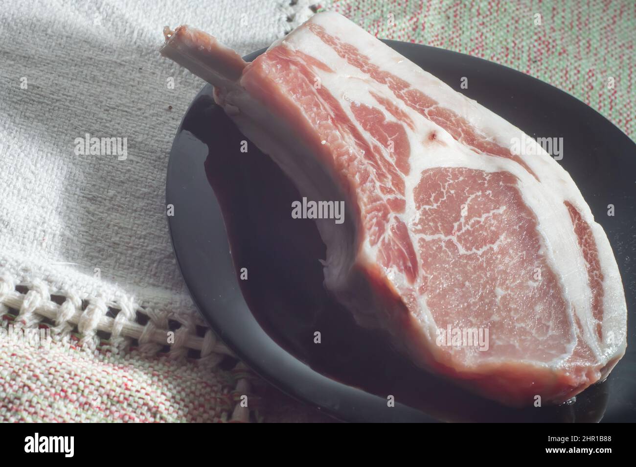 Bistecche di maiale crude di Tomahawk su piastra nera, vista dall'alto. Tre bistecche di maiale crude, pronte per la griglia con vista dall'alto. Foto Stock