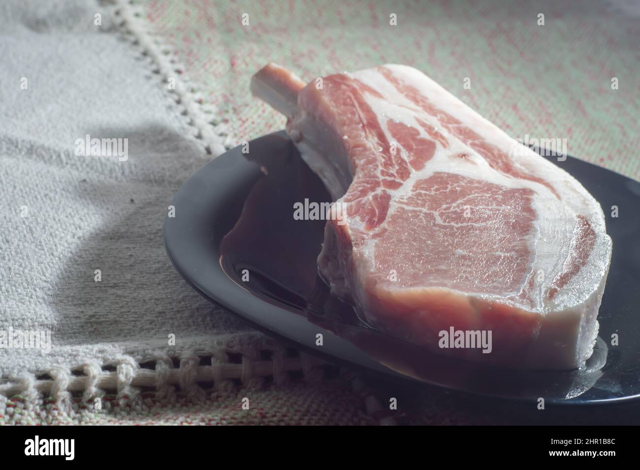 Bistecche di maiale crude di Tomahawk su piastra nera, vista dall'alto. Tre bistecche di maiale crude, pronte per la griglia con vista dall'alto. Foto Stock