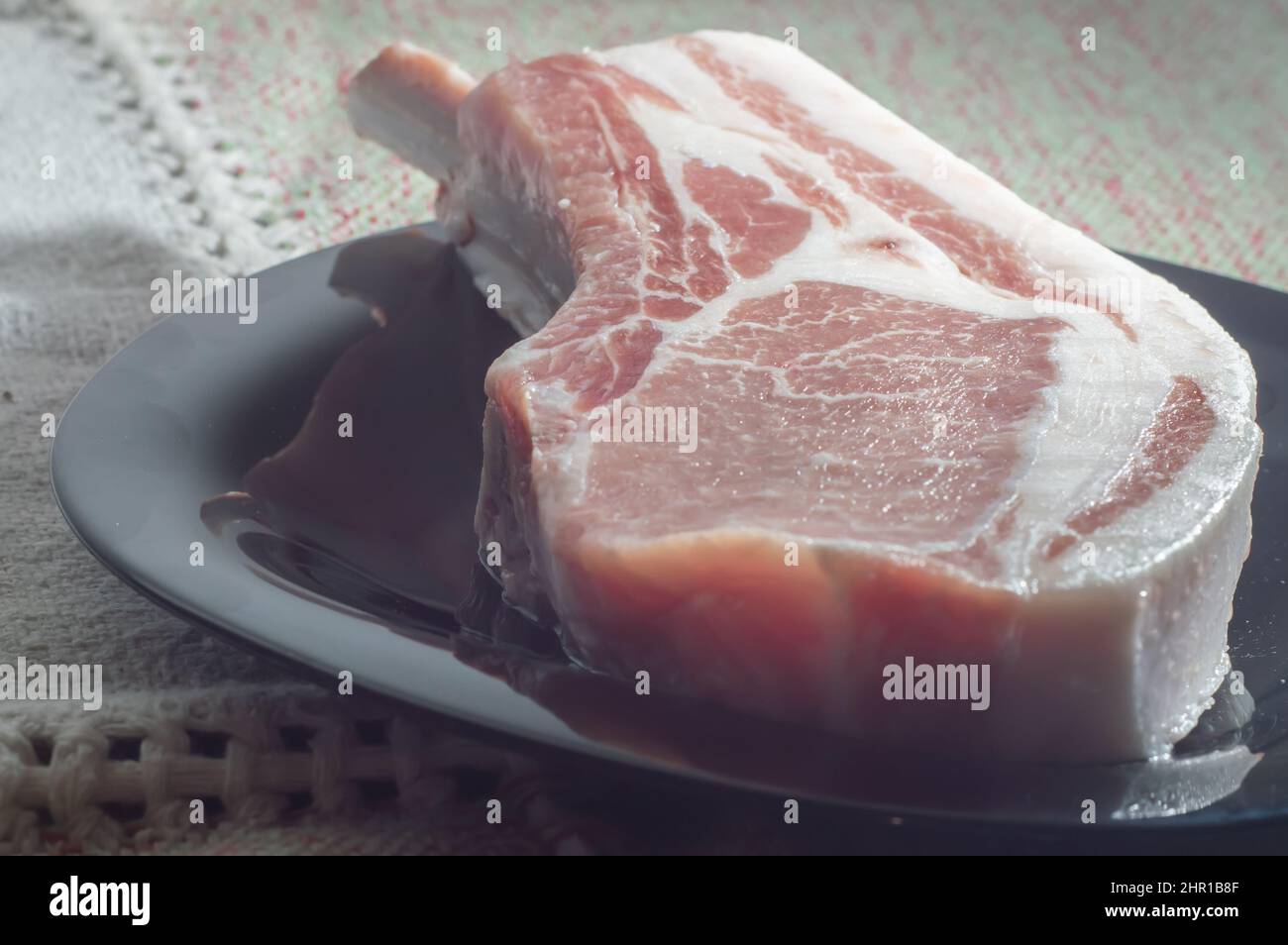 Bistecche di maiale crude di Tomahawk su piastra nera, vista dall'alto. Tre bistecche di maiale crude, pronte per la griglia con vista dall'alto. Foto Stock
