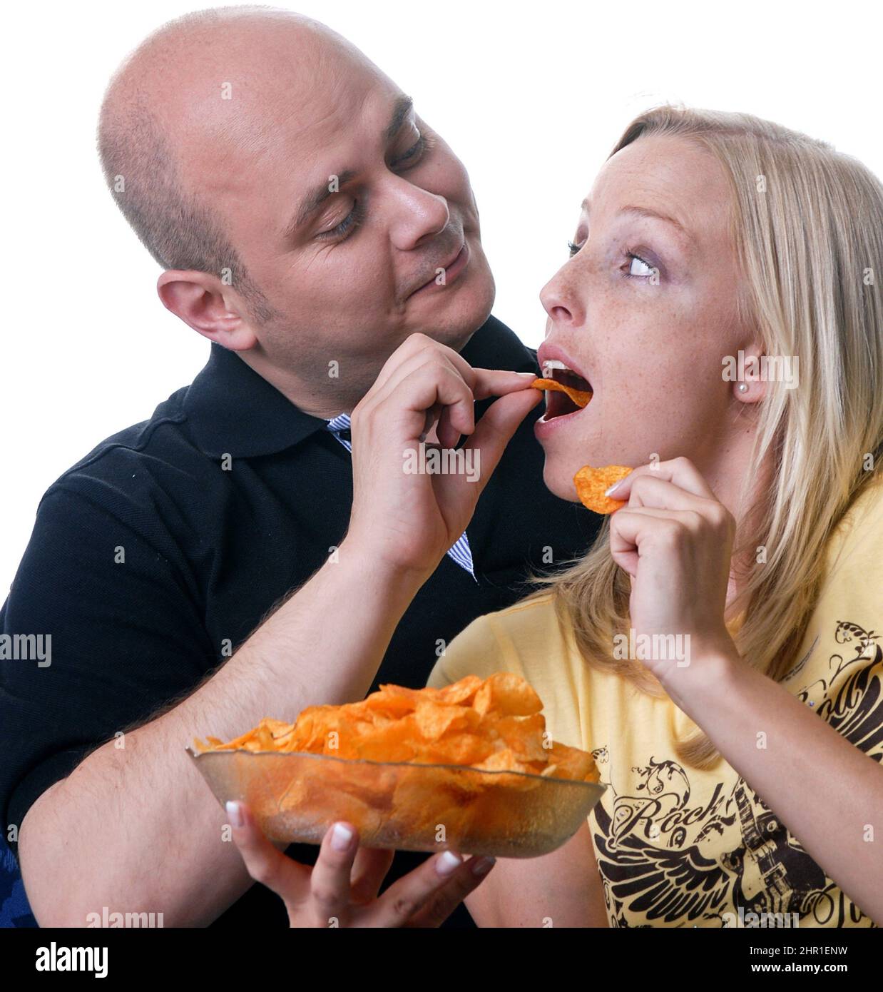La coppia gode di una serata accogliente guardando la TV con una ciotola di patatine Foto Stock