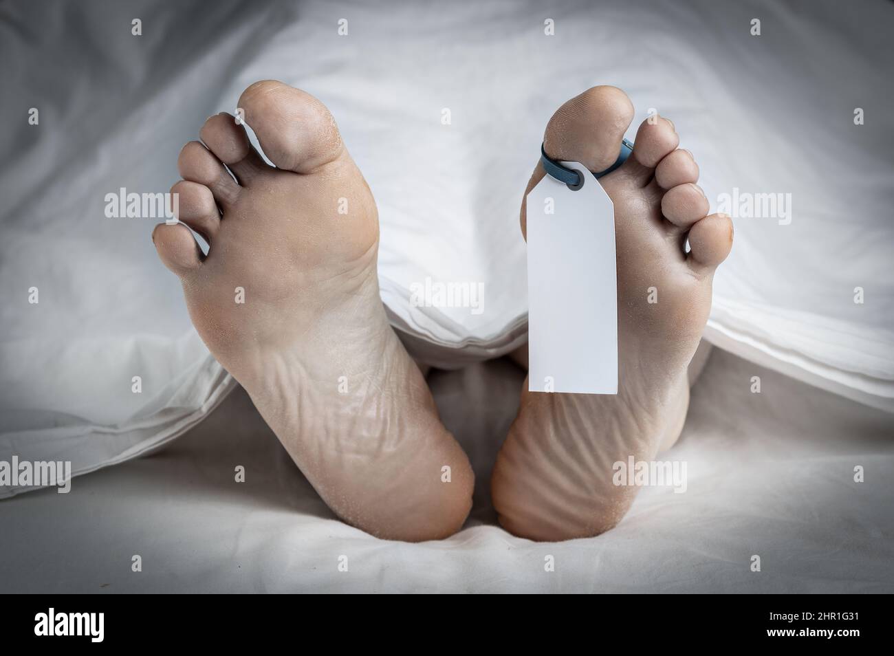Primo piano dei piedi di un cadavere coperto in un foglio; con un'etichetta vuota legata alla punta del piede sinistro; con un'aggiunta di vignetta e spazio per la copia Foto Stock